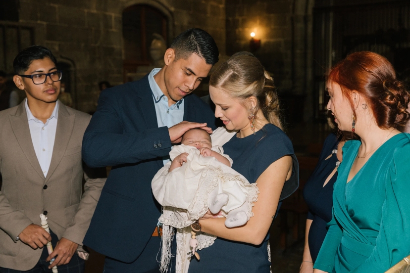 Padres sujetando a niña en el bautizo