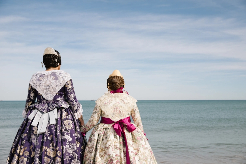 Madre e hija vestidas de fallera mirando hacia el mar en Valencia