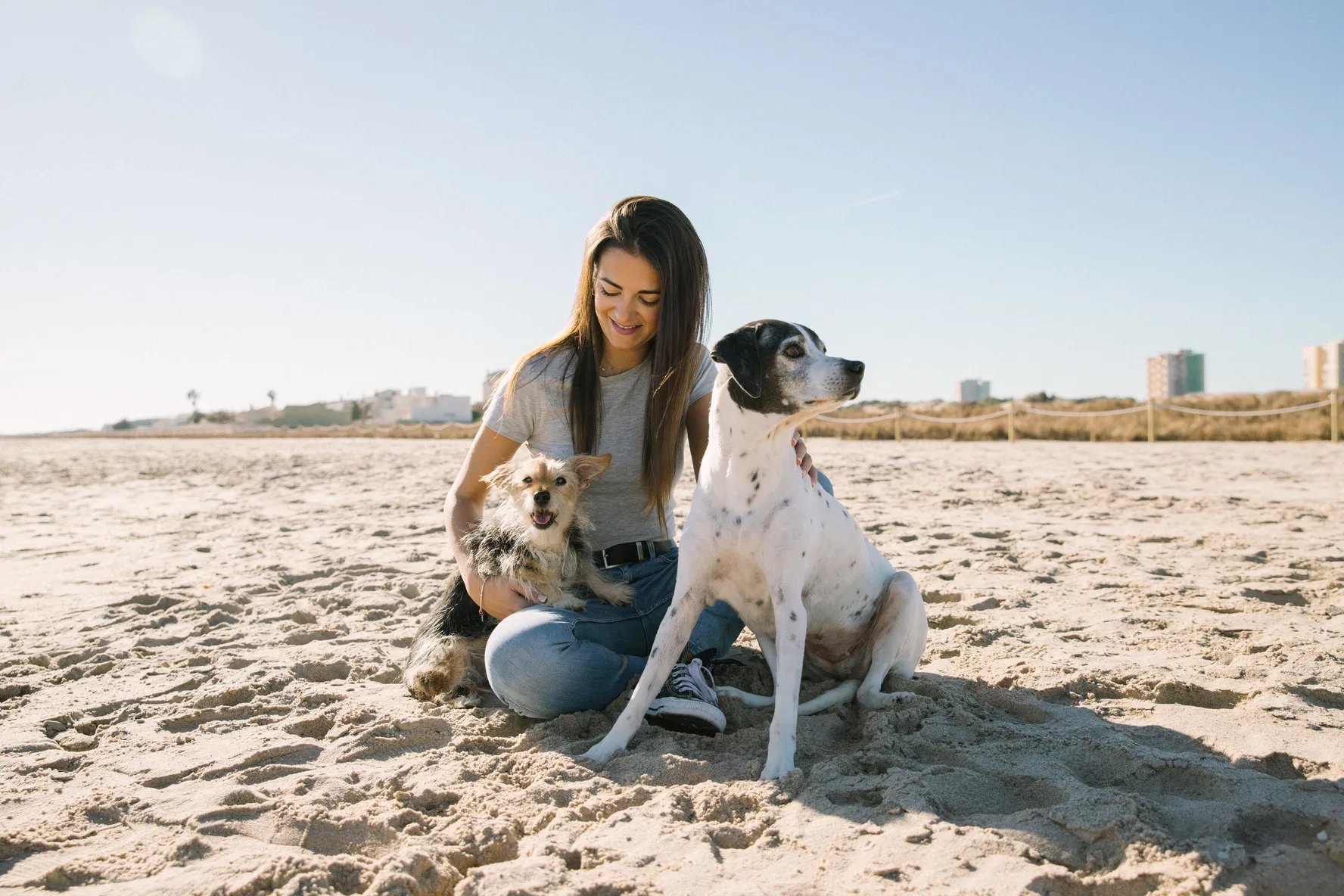 Chica con sus dos perros en la playa disfrutando de un buen momento